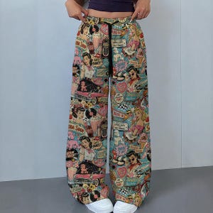 May include: Wide-leg pants featuring a colorful 1950s-inspired print with illustrations of classic cars, diners, jukeboxes, and people. The pants have a teal background, a black drawstring waistband, and a repeating pattern of retro graphics.