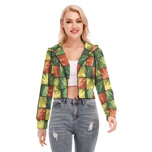 May include: A cropped hoodie with a colorful patchwork design featuring green, yellow, and orange squares with a leaf pattern. The hoodie has a zipper closure and a hood.