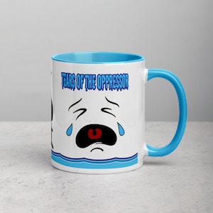 Könnte beinhalten: Eine weiße Keramiktasse mit blauem Rand und Henkel. Die Tasse zeigt ein blaues und weißes Comic-Gesicht mit Tränen und den Text "Tears of the Oppressor" in blau.