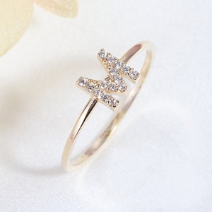 May include: A gold ring featuring a letter M set with small diamonds.