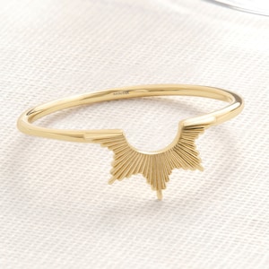 May include: A gold ring with a sunburst design. The ring is made of 14k gold and is stamped with the maker's mark "MINIIK".