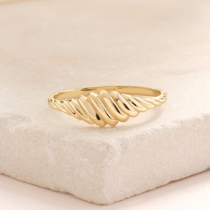 May include: A gold ring with a twisted, textured design. The ring is made of 14k gold.