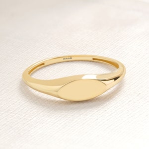Peut inclure: Une bague signet en or avec un dessus lisse de forme ovale. La bague est marquée "MIN14K" à l'intérieur de la bande.