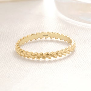 May include: A gold ring with a textured design of small, pointed triangles. The ring is marked "MINI 14K" on the inside.