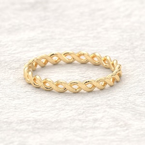 May include: A gold-colored, braided ring with a delicate, intricate design.