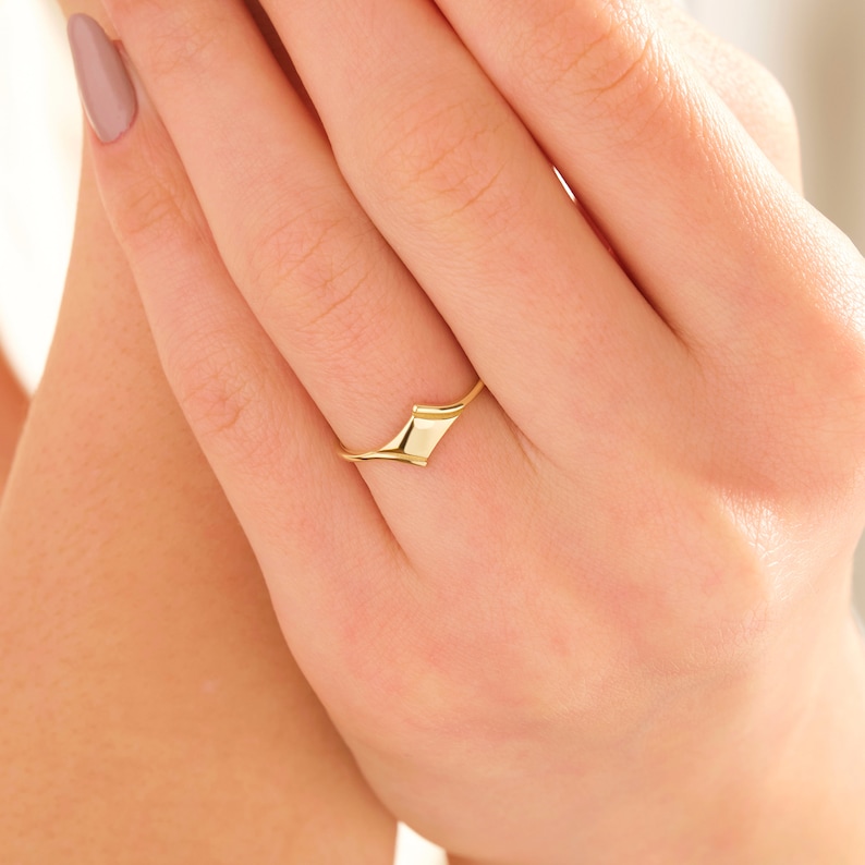 May include: A gold ring with a unique, abstract design. The ring is made of a smooth, polished metal and has a simple, modern style.