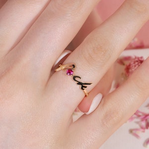 May include: Gold ring featuring a red gemstone and the word "Love" in cursive.