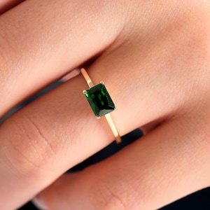 May include: A gold ring with a green emerald-cut gemstone.