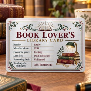 May include: A rectangular metal sign titled BOOK LOVER'S LIBRARY CARD with a silver finish. It features a green desk lamp illuminating a stack of three books, decorative borders, and text fields including Reader: Emily, Member since: 1994, and Fantasy.