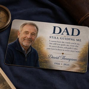 Puede incluir: Una tarjeta conmemorativa rectangular de metal con el retrato de un hombre, un fondo de sendero forestal y el texto: DAD STILL GUIDING ME, I cannot hear the words you'd say, but still you guide me every day. In every choice and path I take, your love is there in every step I make. David Thompson 1956-2025.