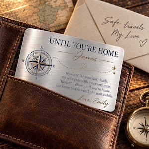 Op de afbeelding: Een rechthoekige, zilverkleurige metalen portemonneekaart met een kompasafbeelding, sterren en de tekst: UNTIL YOU'RE HOME, James, However far your duty leads, my love goes with you every mile, Keep this close until you're home, and know you're worth the wait awhile. Love, Emily.