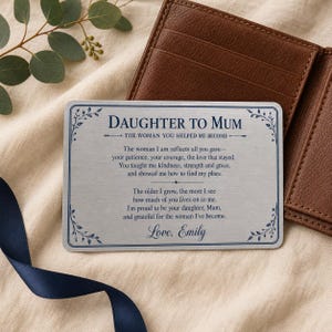 Op de afbeelding: Een rechthoekige zilverkleurige metalen portemonneekaart met donkerblauwe tekst: DAUGHTER TO MUM, THE WOMAN YOU HELPED ME BECOME, gevolgd door een sentimenteel gedicht en de ondertekening Love, Emily, omlijst door een delicate blauwe bladrand.