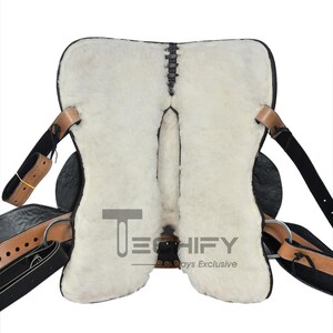 May include: A black and tan leather saddle with a white sheepskin lining. The saddle features leather straps, metal rings, and stitching details. The image includes the text "TECHIFY" and "Always Exclusive".