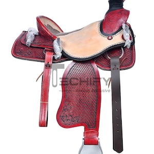 May include: A red leather saddle with intricate tooling and a black leather seat. The saddle has a silver stirrup and a brown leather strap.
