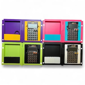 May include: A collection of eight colorful electronic music synthesizers in various colors, including purple, yellow, pink, blue, green, black, and white. Each synthesizer has a screen and numerous buttons.