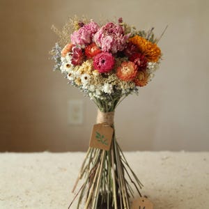 This photo features variation K in a size medium with pink peonies, and orange marigold, daisies, strawflowers and mixed wildflowers and grasses. Organic and naturally air dried flowers. A good size for a bridesmaid, maid of honor, or bridal bouquet, or for a large vase table centerpiece. Mother's Day and Easter florals.