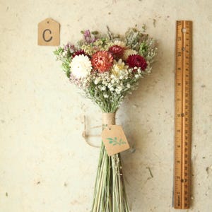 This photo features variation C, a petite dried flower bouquet with peach, burgundy, and  creamy white strawflowers, daisies and wildflowers. Cottage garden wedding florals, Mother's Day and home decor.