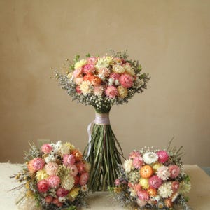 Custom XL Bridal Bouquet with two medium dried flower bridesmaid bouquet laying on each side. Bright pastel tones of creamy white, blush, pink, yellow and peach.