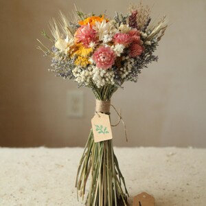 This bouquet features variation H of the listing, with an orange marigold and mix of pink, white and orange strawflowers, ammobium daisies, wildflowers and wild grasses. Size is a Petite Full . Mother's Day, wildflower wedding, bridesmaid proposal floral gifts.
