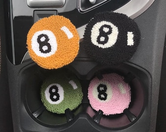 Può includere: Quattro porta bicchieri per auto a tema 8-ball. I porta bicchieri sono realizzati in un materiale morbido e soffice e sono di colore arancione, nero, verde e rosa.