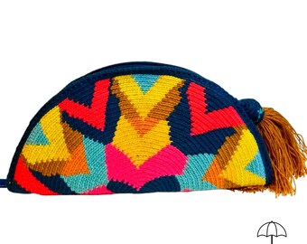 May include: A colorful, half-moon shaped clutch with a geometric pattern in shades of blue, yellow, red, pink, and brown. The clutch has a navy blue zipper and trim, and a brown tassel. The clutch is handmade.