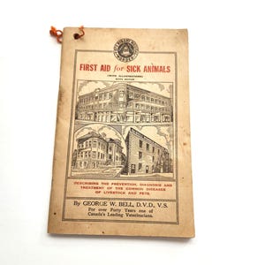 Puede incluir: Libro antiguo titulado "First Aid for Sick Animals" con ilustraciones. La portada es de color beige con texto rojo y negro, con dibujos de edificios. Describe la prevención, el diagnóstico y el tratamiento de enfermedades comunes en ganado y mascotas.