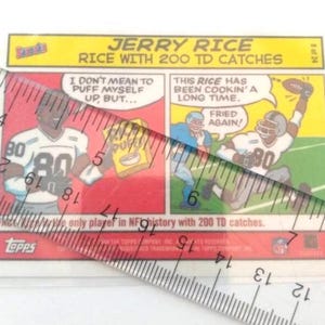 May include: A Topps trading card featuring Jerry Rice. The card has a cartoon illustration of Rice in a football uniform with the number 80. Text includes "JERRY RICE" and "RICE WITH 200 TD CATCHES". The card is in a protective sleeve.