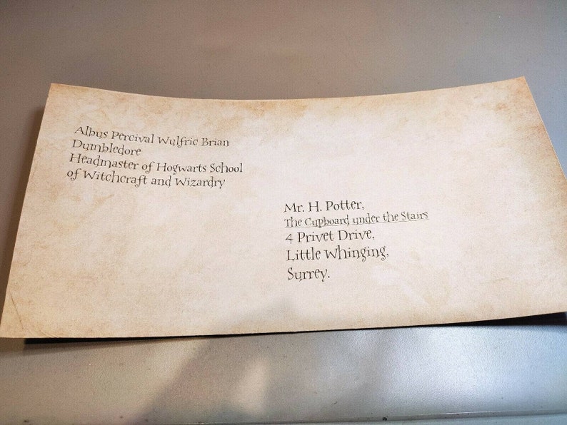 May include: A vintage-looking envelope addressed to Mr. H. Potter, The Cupboard under the Stairs, 4 Privet Drive, Little Whinging, Surrey. The return address is Albus Percival Wulfric Brian Dumbledore, Headmaster of Hogwarts School of Witchcraft and Wizardry.