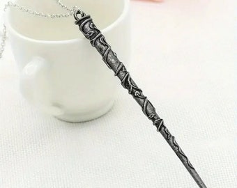 May include: A silver necklace with a wand pendant. The wand is detailed with intricate vine designs.