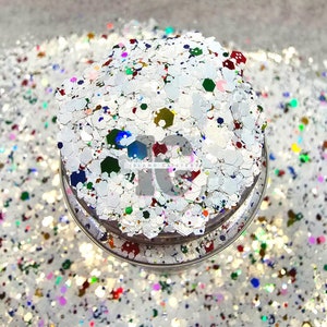 Peut inclure: Paillettes blanches avec des paillettes multicolores. Les paillettes sont dans un pot transparent avec un couvercle argenté. Le pot porte l'inscription "Island Glitter".