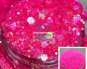 May include: A close-up of a jar filled with pink glitter with iridescent accents. The glitter is a mix of fine and chunky sizes.
