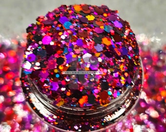 Könnte beinhalten: Nahaufnahme eines mit buntem Glitter gefüllten Glases. Der Glitter ist eine Mischung aus Rot, Orange, Gelb, Grün, Blau, Lila und Schwarz. Der Glitter befindet sich in einem durchsichtigen Glas mit einem silbernen Deckel.
