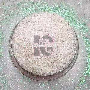 May include: A close-up of a white iridescent glitter in a clear container. The glitter is very fine and has a subtle shimmer. The container has a black label with the text "Island Glitter" on it.