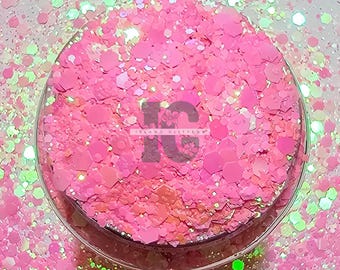 Könnte beinhalten: Pinkfarbener und irisierender Glitter mit holografischem Finish. Der Glitter befindet sich in einem durchsichtigen Behälter vor einem weißen Hintergrund.