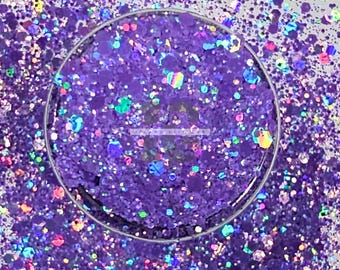 May include: A clear container filled with purple glitter. The glitter particles vary in size and shape, with iridescent and holographic elements that reflect multiple colours. The glitter is scattered around the container, creating a sparkling effect.