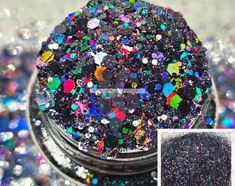 May include: A close-up of a jar filled with black glitter with multi-colored iridescent glitter mixed in. The glitter is in a clear jar with a silver lid. A smaller image of the glitter is shown in the bottom right corner of the image.