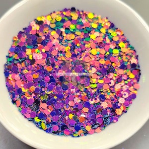 May include: A close-up of iridescent glitter in a variety of shapes and sizes. The glitter is a mix of purple, pink, orange, yellow, and green.
