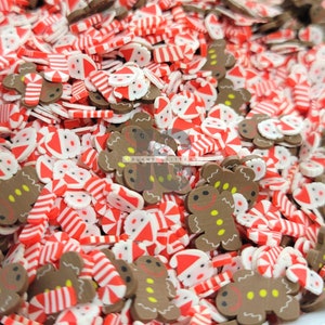 May include: A close-up shot of a pile of Christmas-themed polymer clay slices. The slices feature gingerbread men, Santa faces, and red and white striped candy canes. The gingerbread men are brown with yellow accents, and the Santa faces have red hats and white beards.