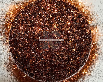May include: A close-up of a jar filled with fine copper glitter. The glitter is a mix of small and large particles, creating a shimmering effect.