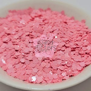 Op de afbeelding: Een kom gevuld met roze glittervlokken. De glitter is een mix van kleine en grote vlokken, met een lichte iriserende glans.