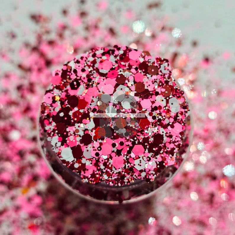 May include: A close-up of a jar filled with pink, red, and white glitter. The glitter is a mix of different sizes and shapes.