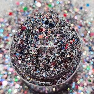 Könnte beinhalten: Nahaufnahme eines Glases gefüllt mit buntem Glitter. Der Glitter ist eine Mischung aus Silber, Schwarz, Rot, Blau und Grün. Der Glitter befindet sich in einem durchsichtigen Glas mit schwarzem Deckel.