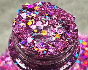 May include: A close-up of a jar filled with iridescent purple, pink, and blue glitter. The glitter is a mix of different sizes and shapes, creating a sparkly and festive look.