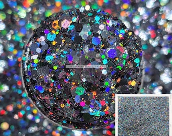 May include: A close-up of iridescent black glitter with a variety of colors, including green, blue, and red. The glitter is in a small container and is surrounded by more glitter.