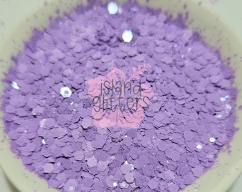 May include: A close-up of a bowl filled with purple glitter. The glitter is in various sizes and shapes, creating a sparkly and iridescent effect.