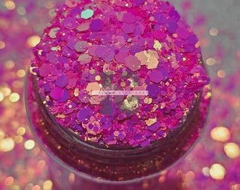 May include: A close-up of a jar filled with pink, purple, and gold glitter. The glitter is iridescent and has a variety of shapes and sizes.