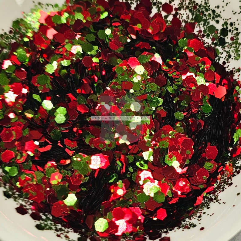 May include: Red, green and black glitter in a variety of shapes and sizes. The glitter is in a white bowl.