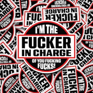 May include: A collection of white stickers with black and red text. The central sticker reads "I'M THE FUCKER IN CHARGE OF YOU FUCKING FUCKS!" in bold, capital letters. Other stickers repeat the phrase "FUCKER IN CHARGE".