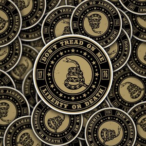 May include: A collection of round stickers featuring a coiled snake and the text "Don't Tread on Me." The stickers have a black and gold color scheme with the words "Liberty or Death" and the number "76."