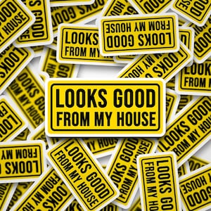 May include: A collection of yellow and black rectangular stickers with the text "LOOKS GOOD FROM MY HOUSE". The stickers are scattered across a white surface, with some overlapping. The text is in a bold, sans-serif font.